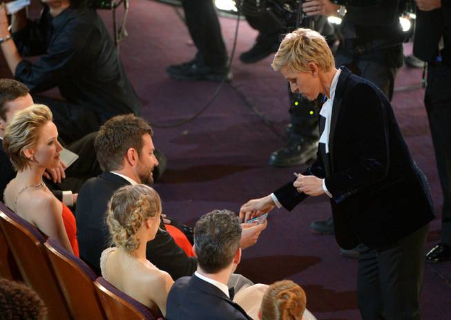 Ellen DeGeneres, right, gives Bradley Cooper a lottery ticket during the Oscars at the Dolby Theatre on Sunday, March 2, 2014, in Los Angeles.  (Photo by John Shearer/Invision/AP)